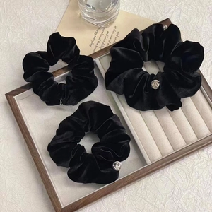Set di tre elastici per capelli in velluto nero con ciondoli in argento su vassoio