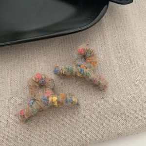 Dettaglio di mini mollette per capelli in peluche lavorato a maglia con pois colorati
