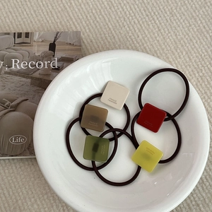 Detailed view of five colorful elastic hair ties with matte square resin pendants
