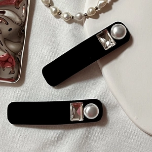 Detail of vintage black velvet hair clips with elegant rhinestones and pearl accents