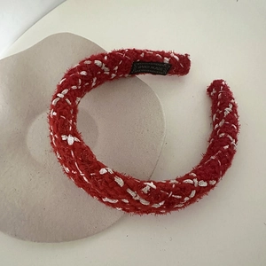 Detailed macro view of a red handmade knitted headband with white cross-stitch on a tray