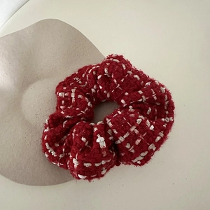 Close-up of red and white plaid tweed hair scrunchie with textured woven fabric