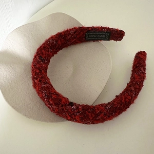 Detail of red tweed padded headband featuring handmade black woven label and shimmer texture