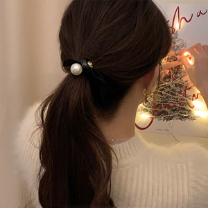 Gros plan sur l'élastique à cheveux camélia et perle avec éclairage festif chaleureux