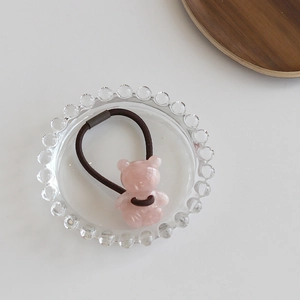 Detailaufnahme eines rosa Bären-Haargummis auf einem dekorativen Glasteller