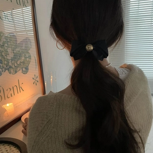 Elegant black satin bow hair clip with vintage gold relief coin displayed on model hair