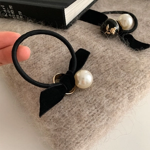 Détail de chouchous en velours vintage avec perles crème et gaufrage floral sur fond tricoté