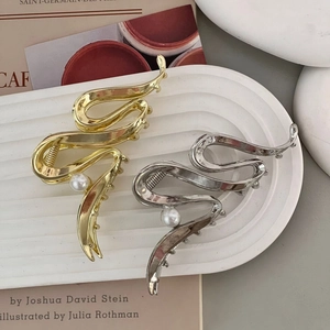 Detail of wavy metal hair claw clips with pearl accents in gold and silver finishes
