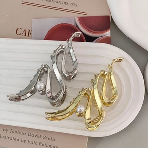 Detailed close-up of gold and silver metal hair claws with elegant pearls in a tray