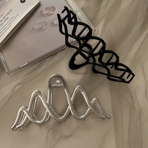Detailaufnahme der großen Haarklammern in Metallsilber und Mattschwarz mit Wellenform