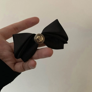 Detailed close-up of a vintage bronze relief emblem on a black satin hair clip ribbon