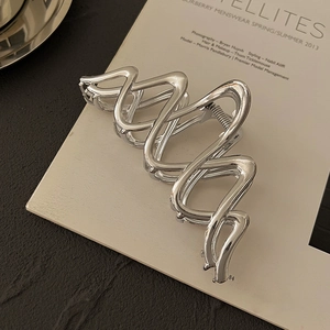 Detailansicht der silbernen Wellen-Haarklammer aus Metall auf einem Modemagazin