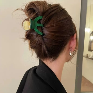 Elegant emerald green marble acetate hair claw clip with gold leaf detail on brunette hair