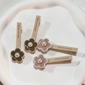 Detail of floral hair clips with pearls and Creation France text on a white tray