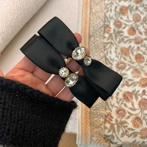 Detail of elegant black satin bow hair clips featuring crystal rhinestones and pearls