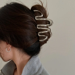 Detail of a large wavy silver metal hair claw clip styled on a woman's hair