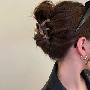 Classic dark brown tortoiseshell acetate hair claw clip shown on a minimalist bun hairstyle