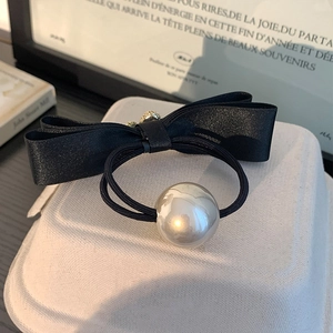 Elegant black satin bow hair tie with a large pearl and rhinestone detail on white stand