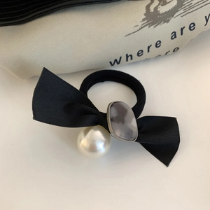Detailansicht eines eleganten Haargummis mit schwarzer Schleife und großer Perle