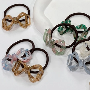 Close-up of tortoise shell and marble textured acetate bow hair ties in various colors