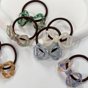 Detailed close-up of marble pattern hollow bow hair ties on white display stand