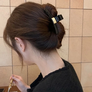 Details von schwarzer Haarklammer mit Gold-Element in eleganter Hochsteckfrisur