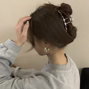 Elegant silver wavy metal hair claw and minimalist double hoop earrings on model