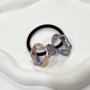 Detail of ribbon hair tie with marble texture resin bow on a white ceramic tray