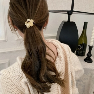 Detailed back view of a floral elastic hair tie worn on a ponytail in cozy indoor setting
