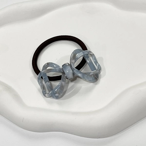 Close-up of blue marble pattern acetate bow hair tie on a white decorative tray