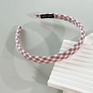 Detailed view of pink and white checkered fabric headband with handmade woven label