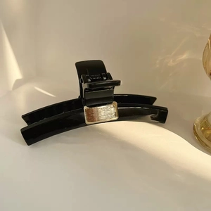 Minimalistische schwarze Haarklammer mit goldenem Metallinlay für Damen auf weißem Grund