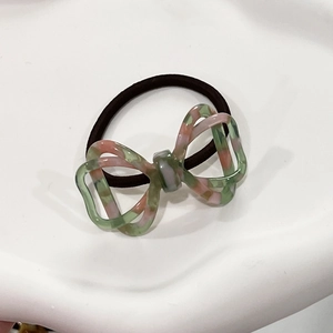 Macro view of 3D hollow bow hair tie with green and pink tortoiseshell pattern
