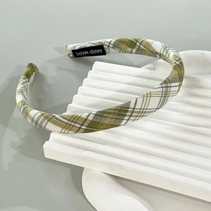 Detail of green and white plaid fabric headband with a woven HAND-MADE label inside