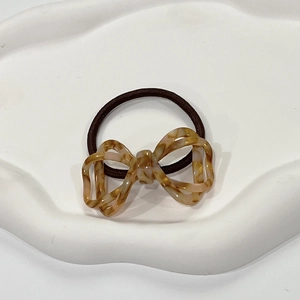 Detail of tortoiseshell pattern bow hair tie on a white minimalist display tray