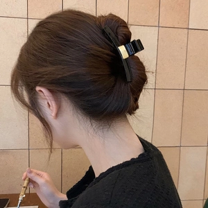 Eleganter schwarzer Haarklammer mit Gold-Schnalle an einer Hochsteckfrisur