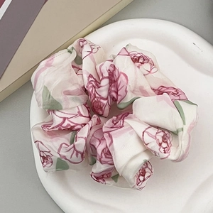 Dettaglio scrunchie in chiffon floreale con stampa rose rosa su vassoio di ceramica