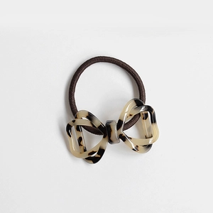 Close-up of brown elastic hair tie with amber resin bow featuring hollow-out pattern