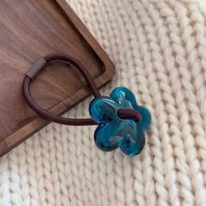 Detail of lake blue resin flower pendant on dark brown high-elasticity hair tie