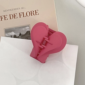 Detail shot of the matte rose pink heart claw clip on a French style magazine page