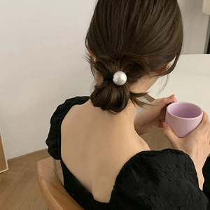 Élastique à cheveux noir avec grande perle champagne porté en chignon bas élégant