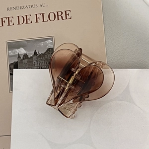 Detailed view of amber heart-shaped acrylic hair claw with golden spring mechanism
