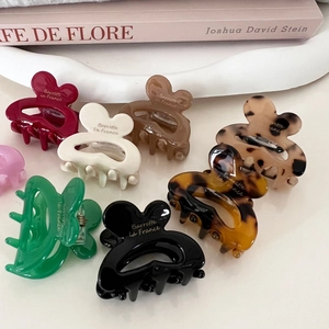 Colorful floral resin hair clips with golden French lettering on a stylish desk setup
