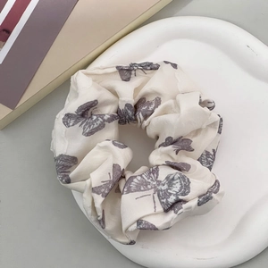Dettaglio dell'elastico in tessuto crema con motivi a farfalla viola su vassoio bianco