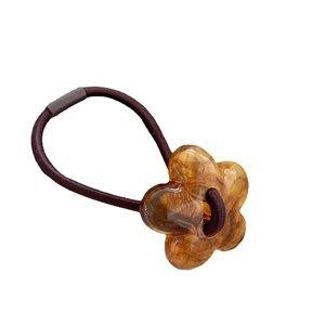 Elastic hair tie featuring an amber tortoiseshell resin flower charm on a white background