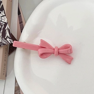 Detail van roze strik haarspelden met glanzende harsafwerking op wit keramiek bord