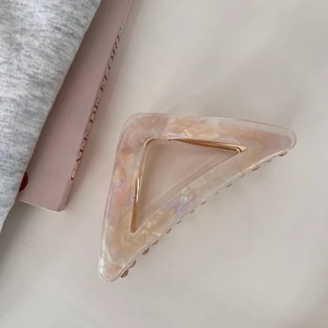 Pink marble acetate triangle hair claw clip with gold spring on a stylish cafe background