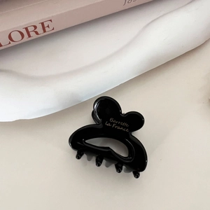 Detail of black butterfly hair clip with gold Barrette la France logo on ceramic tray