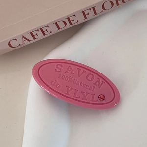 Pink oval acrylic hair clip with SAVON relief lettering and a sparkling rhinestone