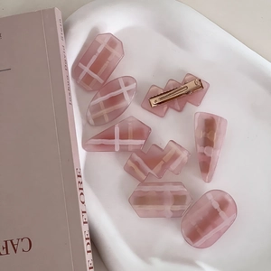 Pink checkered hair clip set with eight geometric shapes on a white ceramic tray